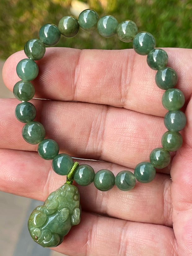 7mm natural Type A Burmese jade beads showing gentle translucency, deep apple green hues, and a hand-carved Pixiu pendant on the wrist