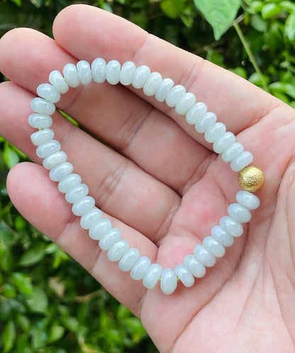 7.7mm natural Type A Burmese jade beads showing gentle translucency, icy green colors, and a matte gold accent on the wrist