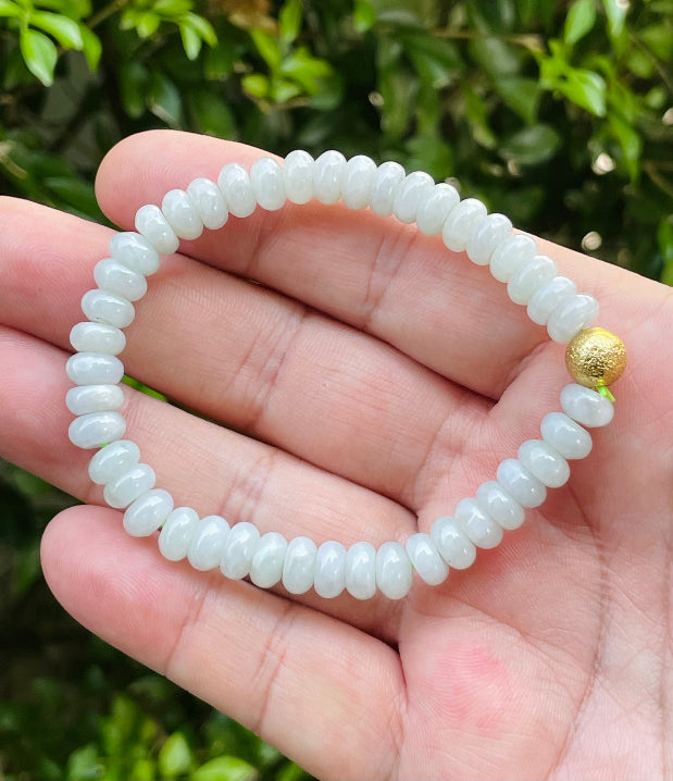 7.7mm natural Type A Burmese jade beads showing gentle translucency, icy green colors, and a matte gold accent on the wrist