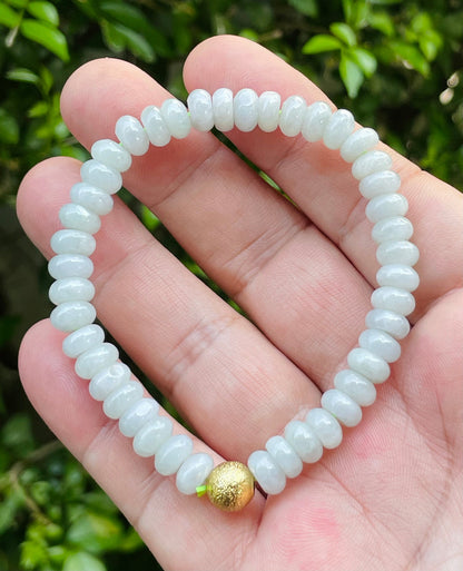 7.7mm natural Type A Burmese jade beads showing gentle translucency, icy green colors, and a matte gold accent on the wrist