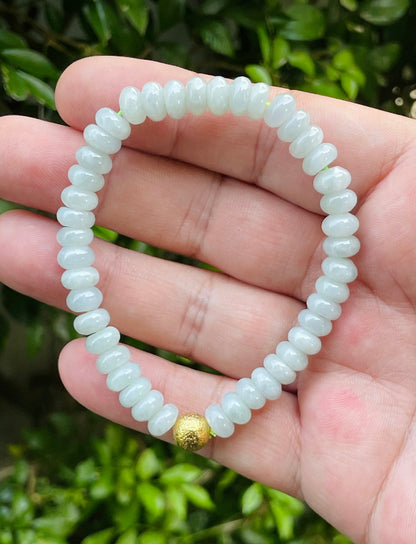 7.5mm natural Type A Burmese jade beads showing gentle translucency, icy green colors, and a matte gold-tone accent on the wrist