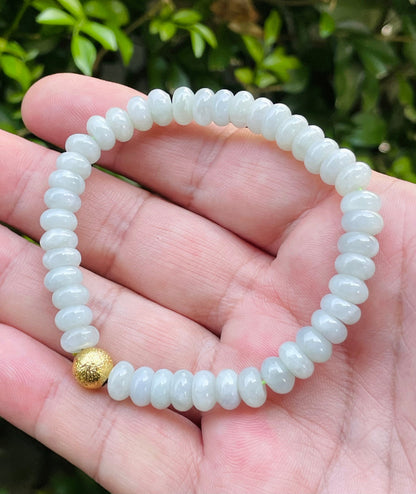 7.5mm natural Type A Burmese jade beads showing gentle translucency, icy green colors, and a matte gold-tone accent on the wrist