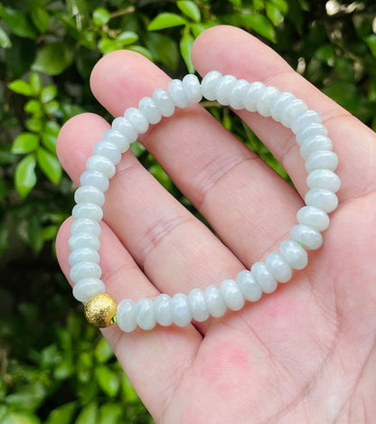 7.5mm natural Type A Burmese jade beads showing gentle translucency, icy green colors, and a matte gold-tone accent on the wrist
