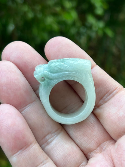 Hand holding a Size US 9.25 Grade A Burmese jadeite ring featuring a detailed hand-carved dragon motif in icy bluish-white and apple green, item JDR004