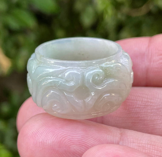 Hand holding a Size US 11.5 Grade A Burmese jadeite thumb ring featuring a full hand-carved floral motif in icy translucent apple green and milky white, item JRN038