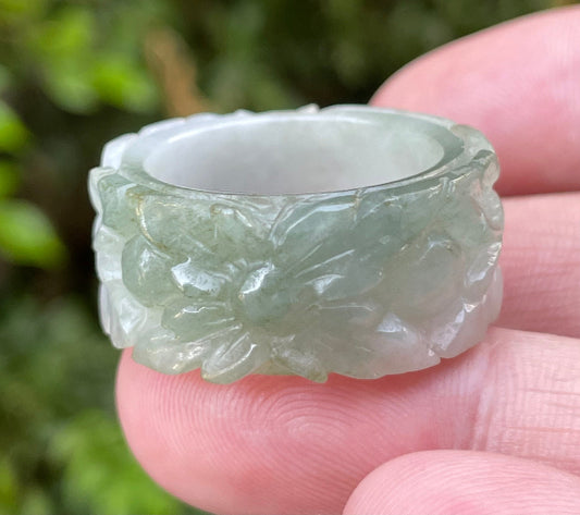 Hand holding a Size US 12 Grade A Burmese jadeite thumb ring featuring a full hand-carved floral motif in icy apple green and milky white, item JRN040