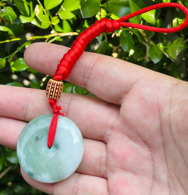Untreated Type A Burmese jade pendant showing semi-gloss luster with beautiful green and white colors on a vivid red adjustable cord