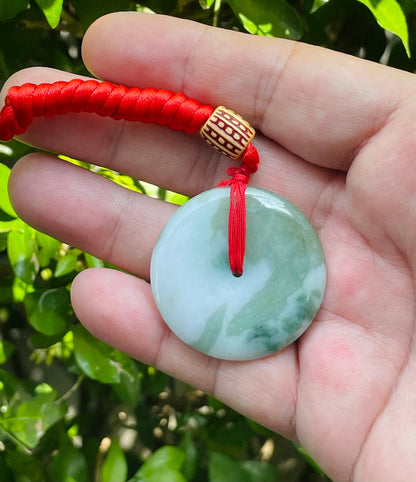 Untreated Type A Burmese jade pendant showing semi-gloss luster with beautiful green and white colors on a vivid red adjustable cord