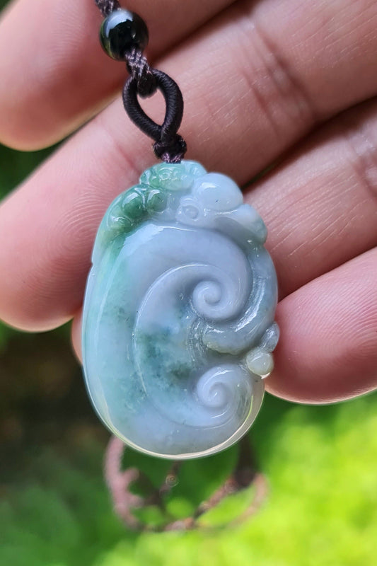 Untreated Type A Burmese jade pendant showing semi-translucent luster with beautiful green and white colors on a dark brown woven cord