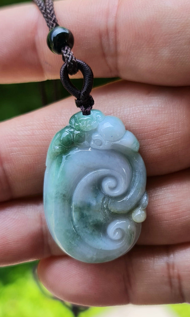 Untreated Type A Burmese jade pendant showing semi-translucent luster with beautiful green and white colors on a dark brown woven cord
