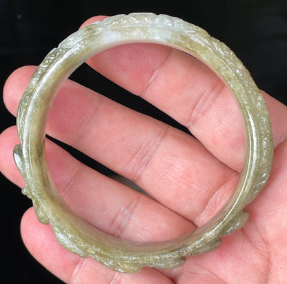 Solid icy green and milky white natural Type A Burmese jade bangle bracelet with carved dragon design, size 58.9mm