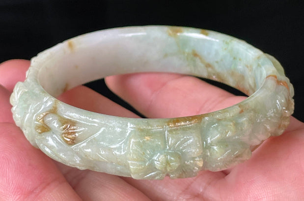 Solid icy apple green, milky white, and honey orange natural Type A Burmese jade bangle bracelet with carved floral design, size 57mm