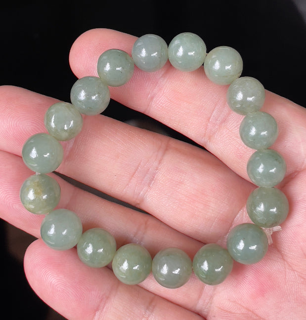 Hand-shaped 10.5mm natural Type A Burmese jade beads showing gentle translucency and icy green colors on the wrist