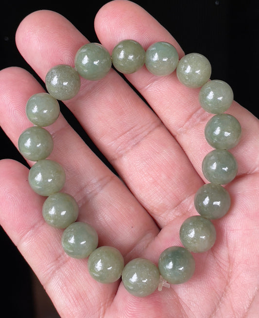 Hand-shaped 10mm natural Type A Burmese jade beads showing gentle translucency and icy green colors on the wrist