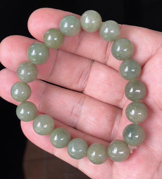 Hand-shaped 10mm natural Type A Burmese jade beads showing gentle translucency and icy green colors on the wrist