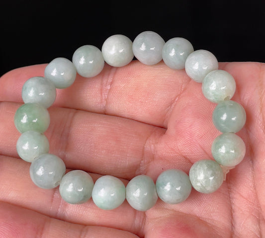 Hand-shaped 10.5mm natural Type A Burmese jade beads showing gentle translucency and bluish green colors on the wrist