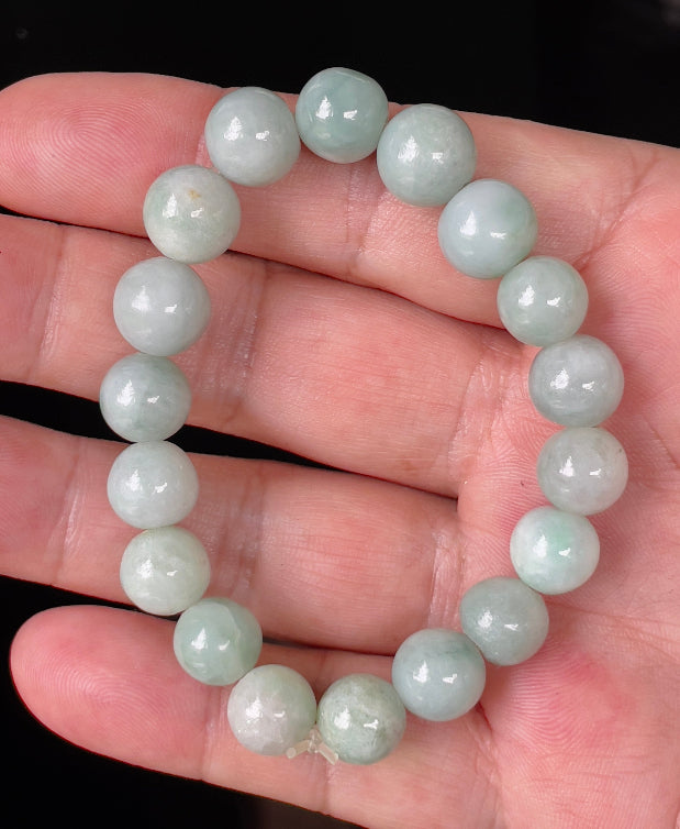 Hand-shaped 10.5mm natural Type A Burmese jade beads showing gentle translucency and bluish green colors on the wrist