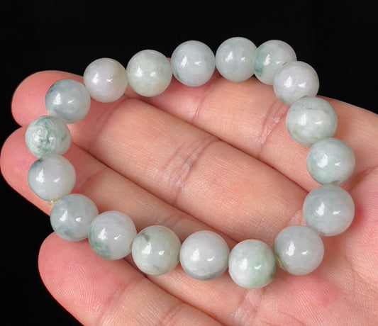 Hand-shaped 10.4mm natural Type A Burmese jade beads showing gentle translucency and mixed green colors on the wrist