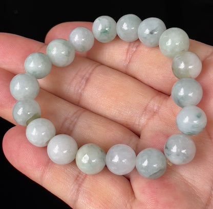 Hand-shaped 10.4mm natural Type A Burmese jade beads showing gentle translucency and mixed green colors on the wrist