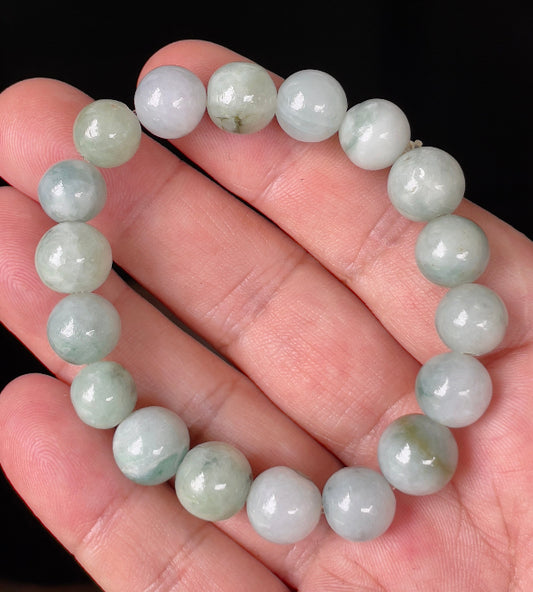 Hand-shaped 10.6mm natural Type A Burmese jade beads showing gentle translucency and mixed green colors on the wrist