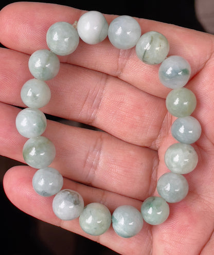 Hand-shaped 10.6mm natural Type A Burmese jade beads showing gentle translucency and mixed green colors on the wrist