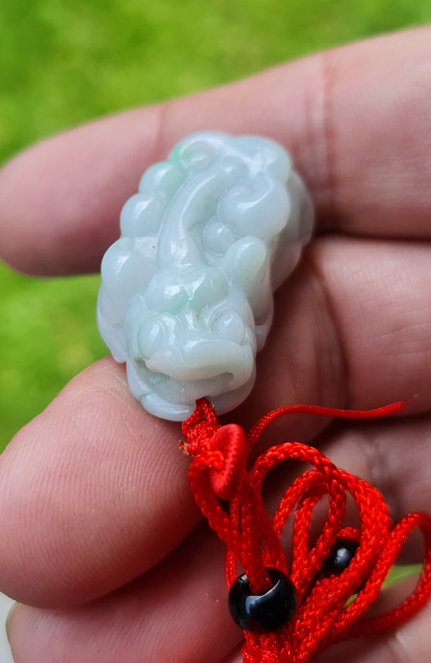 Untreated Type A Burmese jade pendant showing translucent luster with beautiful icy blue and soft green colors on an adjustable red cord