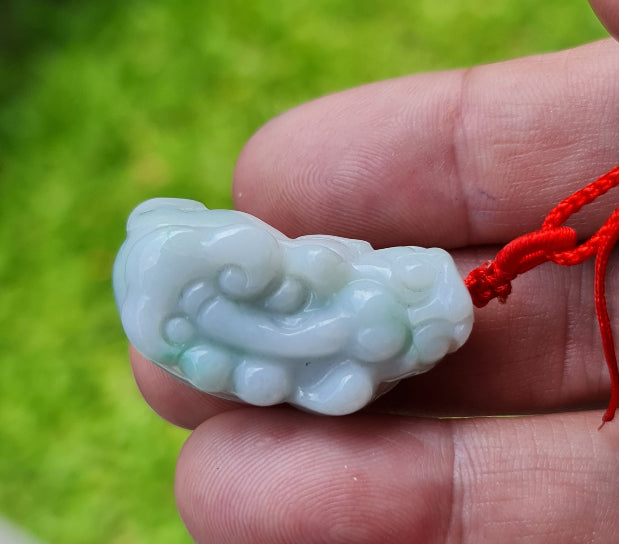 Untreated Type A Burmese jade pendant showing translucent luster with beautiful icy blue and soft green colors on an adjustable red cord