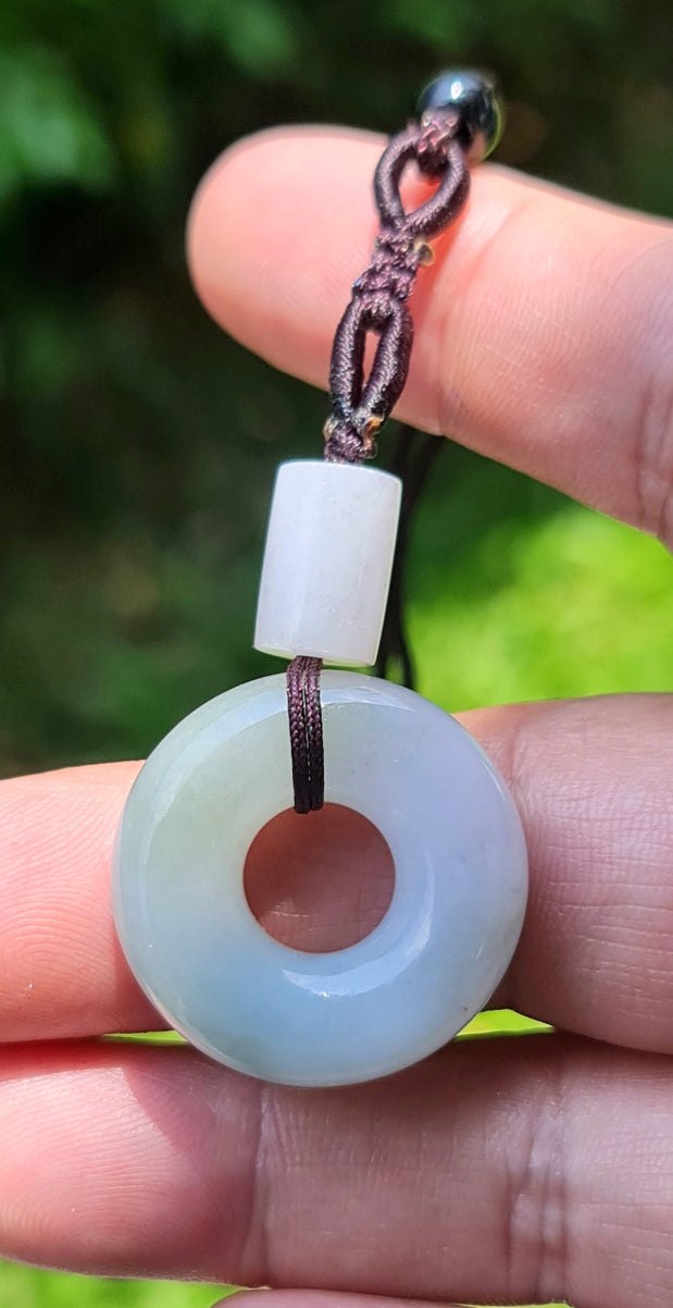 Untreated Type A Burmese jade pendant showing translucent luster with beautiful icy violet and soft green colors on a handwoven cord