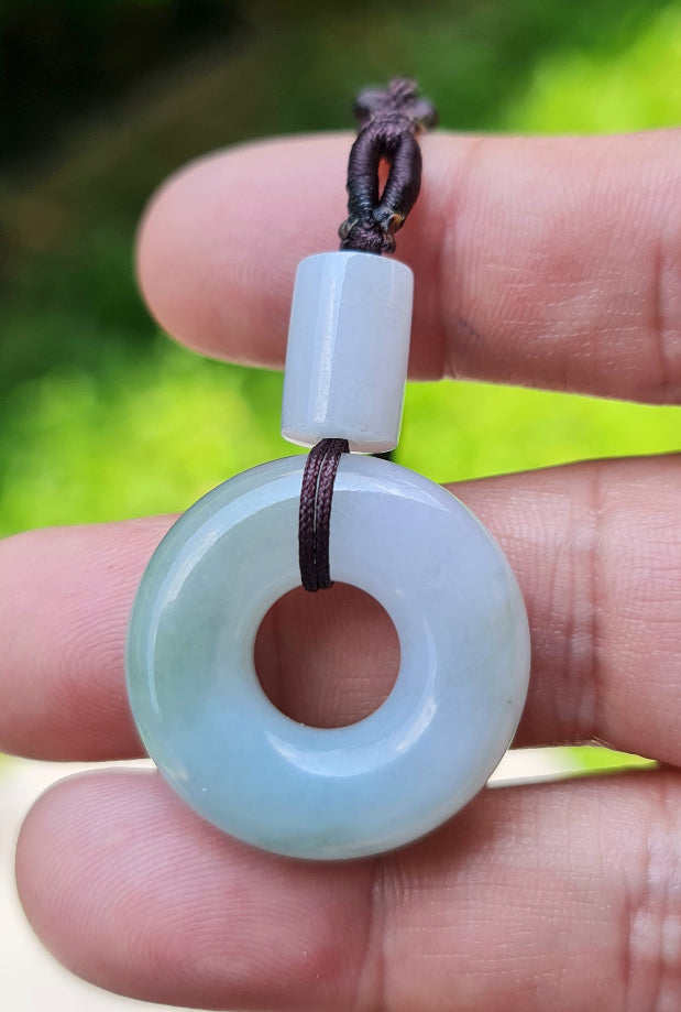 Untreated Type A Burmese jade pendant showing translucent luster with beautiful icy violet and soft green colors on a handwoven cord