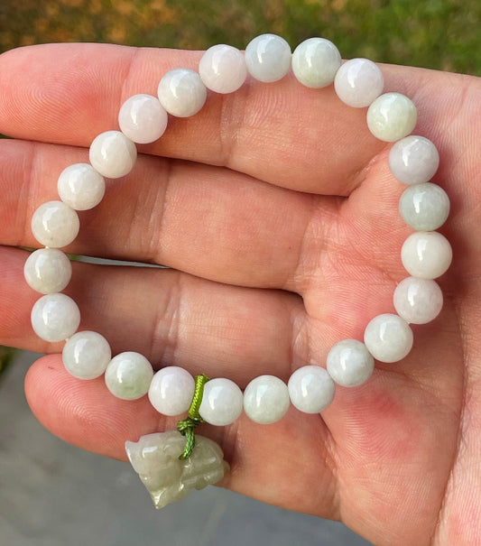 8mm natural Type A Burmese jade beads showing gentle translucency, milky white and pale green hues, and a hand-carved tiger pendant on the wrist