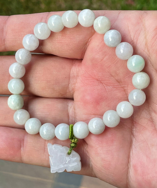 8mm natural Type A Burmese jade beads showing gentle translucency, white and icy green hues, and a hand-carved tiger pendant on the wrist