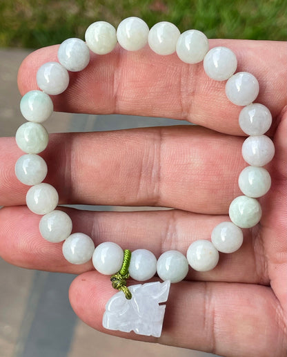 8mm natural Type A Burmese jade beads showing gentle translucency, white and icy green hues, and a hand-carved tiger pendant on the wrist