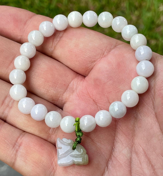 7.8mm natural Type A Burmese jade beads showing gentle translucency, white and lavender hues, and a hand-carved tiger pendant on the wrist