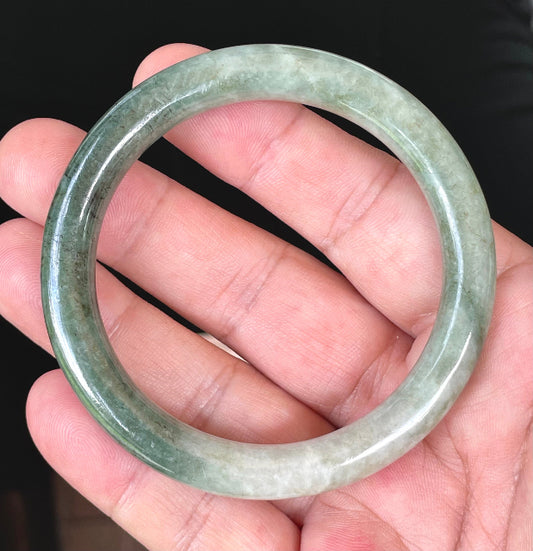 Close-up of a 56.8mm natural Grade A Burmese jadeite bangle featuring icy apple green and milky white hues, item JB403