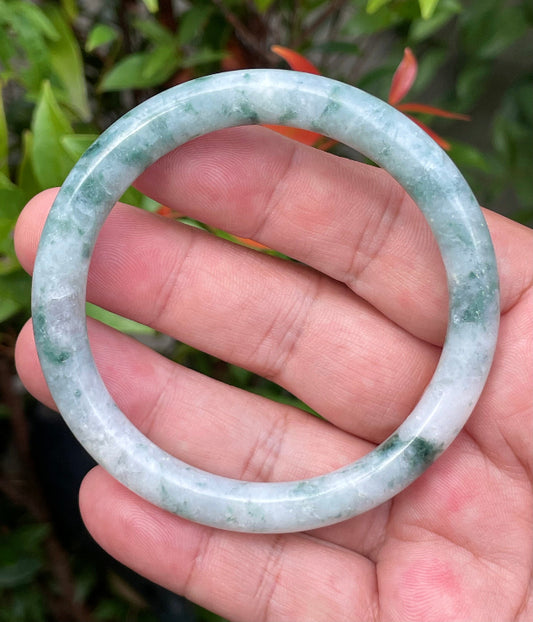 Close-up of a 58.7mm natural Grade A Burmese jadeite bangle featuring icy bluish imperial green and milky white hues, item JB946