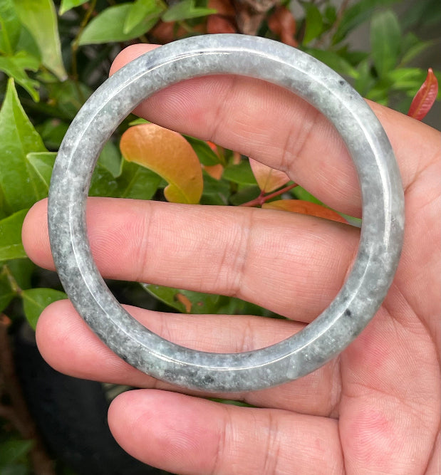 Close-up of a 59.2mm natural Grade A Burmese jadeite bangle featuring icy grayish black and milky white hues, item JB945