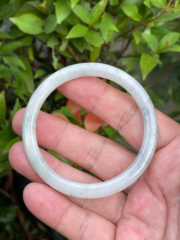 Close-up of a 56.7mm natural Grade A Burmese jadeite bangle featuring icy greyish milky white and green hues, item JB751