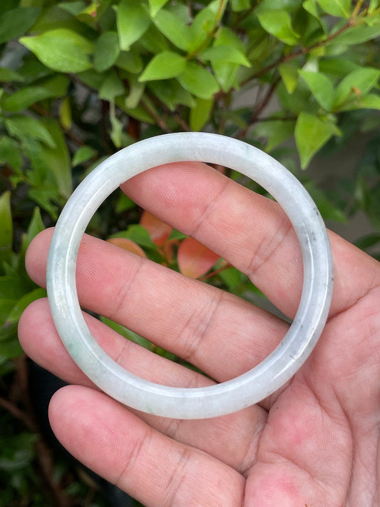 Close-up of a 56.7mm natural Grade A Burmese jadeite bangle featuring icy greyish milky white and green hues, item JB751