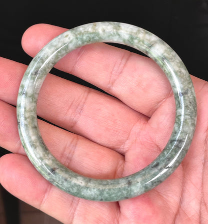 Close-up of a 57mm natural Grade A Burmese jadeite bangle featuring icy imperial green, apple green, and milky white hues, item JB372