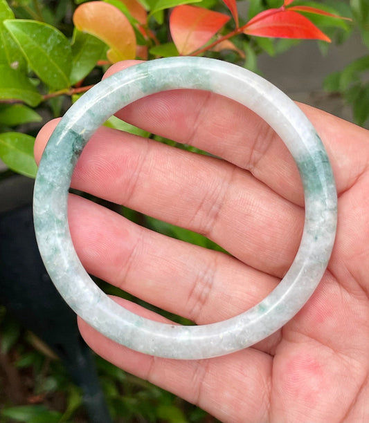 Close-up of a 59.5mm natural Grade A Burmese jadeite bangle featuring icy imperial green and milky white hues, item JB948
