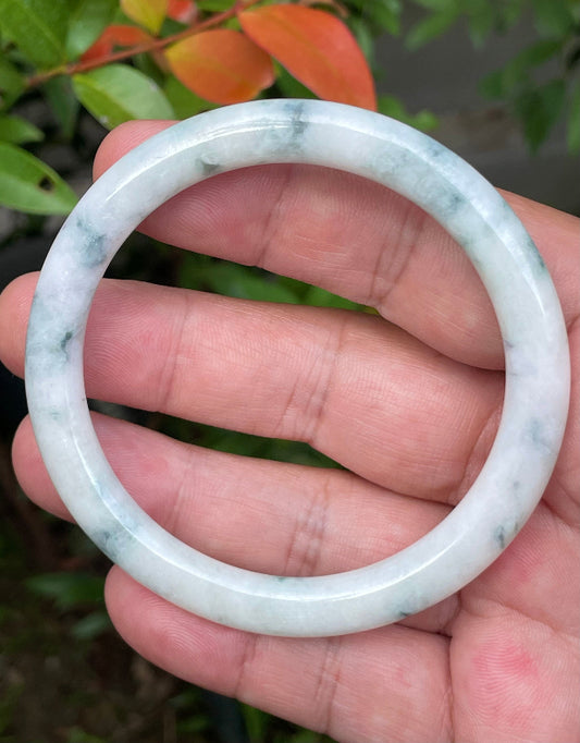 Close-up of a 59mm natural Grade A Burmese jadeite bangle featuring icy imperial green and milky white hues, item JB953