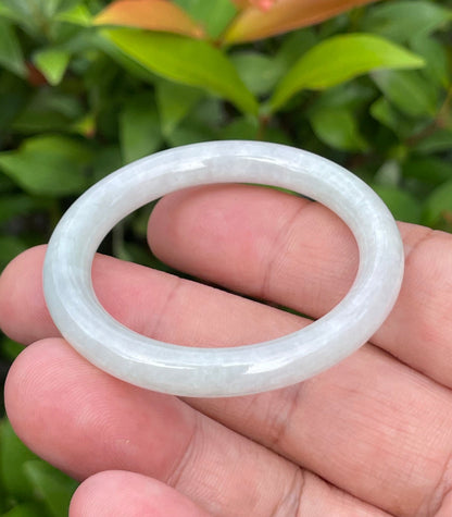 Handcrafted genuine Grade A Burmese jadeite infant bangle showcasing a translucent bright green and white appearance