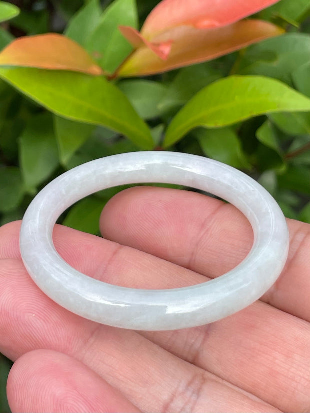 Handcrafted genuine Grade A Burmese jadeite infant bangle showcasing a translucent bright green and white appearance