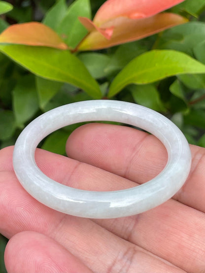 Handcrafted genuine Grade A Burmese jadeite infant bangle showcasing a translucent bright green and white appearance