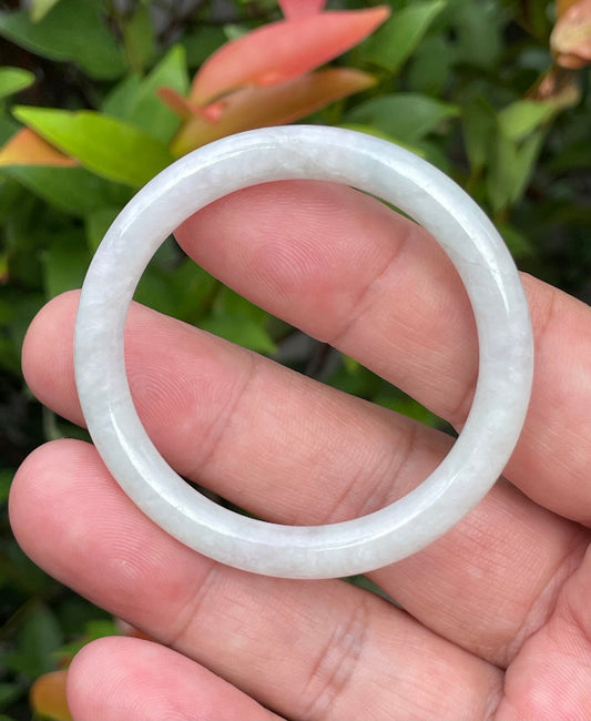 Close-up of a 43mm infant natural Grade A Burmese jadeite bangle featuring icy milky white and apple green hues, item JB891