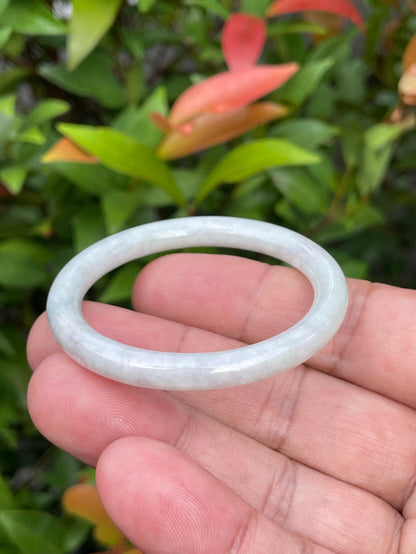 Handcrafted genuine Grade A Burmese jadeite infant bangle showcasing a translucent bright green and white appearance