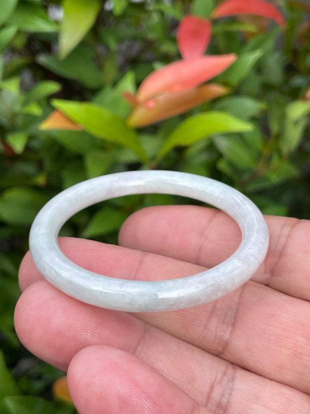 Handcrafted genuine Grade A Burmese jadeite infant bangle showcasing a translucent bright green and white appearance