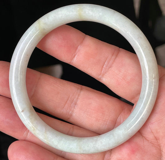 Close-up of a 58.6mm natural Grade A Burmese jadeite bangle featuring icy milky white, apple green, and yellow veins, item JB240