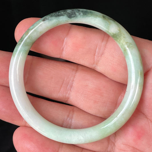 Close-up of a 50.7mm natural Grade A Burmese jadeite bangle featuring icy milky white, forest, apple, and imperial green hues, item JB246