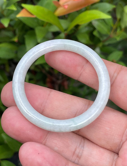 Close-up of a 42.5mm infant natural Grade A Burmese jadeite bangle featuring icy milky white and imperial green hues, item JB887